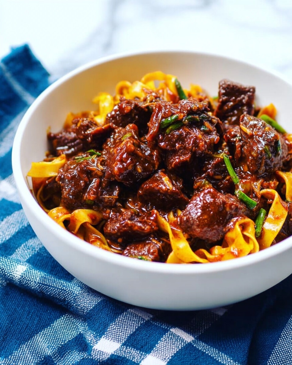 A white bowl filled with thick, dark brown pieces of meat mixed with wide yellow noodles and small green herb bits. The glossy sauce coats the meat and noodles, giving a shiny look. The bowl sits on a blue cloth with a white check pattern, and the background is a smooth white marbled texture. Photo taken with an iphone --ar 4:5 --v 7
