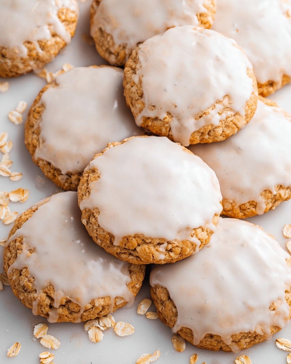 The image shows a close-up of round cookies arranged in rows on a metal cooling rack. Each cookie has two layers: a soft golden-brown base with a textured, slightly crumbly surface, topped with a smooth white icing that slightly drips over the edges. The cookies are placed on a white marbled surface that can be seen below the rack. The photo has a clean and bright look, focusing on the front cookie with the rest blurred in the background. photo taken with an iphone --ar 4:5 --v 7