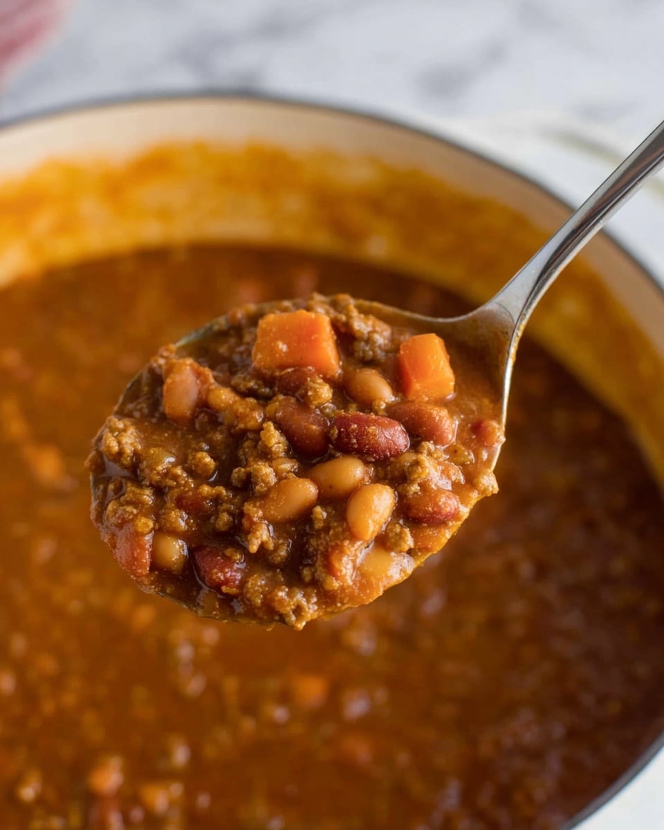 A close-up of a metal spoon holding thick, hearty stew with visible layers of brown beans, small orange carrot chunks, and ground meat pieces all mixed in a rich, brown sauce. The background is a white marbled texture with a white pot filled with the same stew, showing a slightly orange tint near the top edge, and the spoon is raised above it. The textures look chunky and smooth together, with small bits clearly visible in the sauce photo taken with an iphone --ar 4:5 --v 7