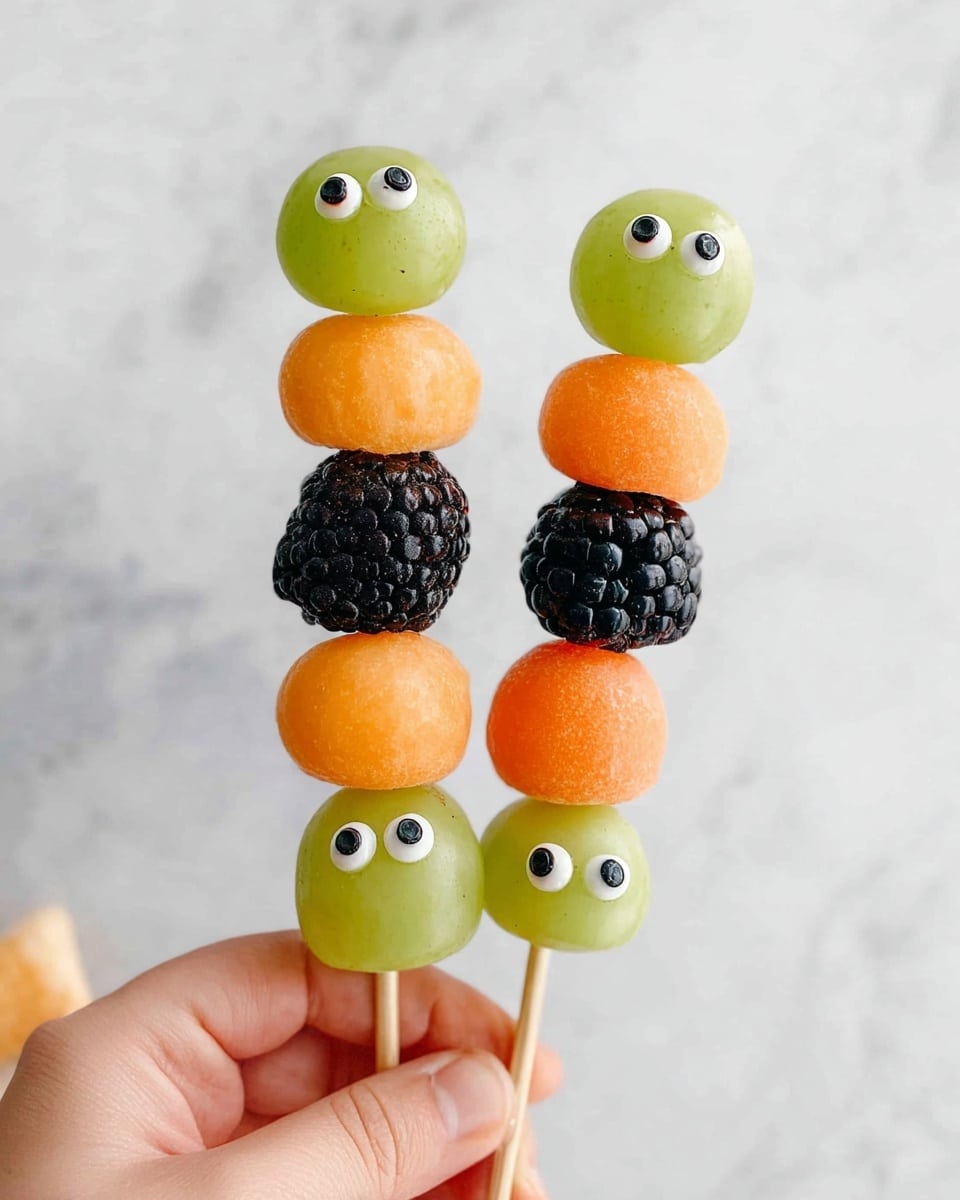 The image shows several fruit skewers laid out side by side on a white plate with a white marbled surface underneath. Each skewer has three layers of fruit: a round orange melon ball on the top and bottom, and a green grape in the middle. The grapes have small edible eyes, making them look like little faces. Between the melon balls and grapes, there is a black blackberry in the center, giving a textured, bumpy look. The colors on the skewers are bright orange, dark black, and fresh green, creating a playful and colorful fruit arrangement. photo taken with an iphone --ar 4:5 --v 7