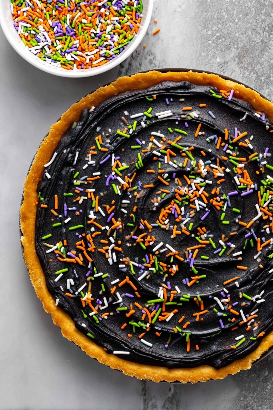 Halloween Pumpkin Spice Cookie Cake, pumpkin spice cookies, Halloween dessert recipes, festive cookie cake, fall pumpkin treats - A round tart with a golden-brown crust forms the base layer, topped with a thick, smooth layer of black frosting spread evenly across the surface with visible swirl textures. Colorful sprinkles in green, orange, white, and purple are scattered evenly over the black frosting, adding bright pops of color. A white bowl filled with the same sprinkles is placed above the tart on a white marbled surface, visible in the top right corner of the image. photo taken with an iphone --ar 2:3 --v 7