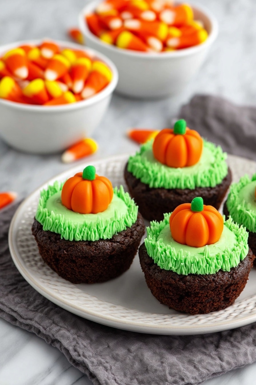 Pumpkin Patch Brownie Bites, fall dessert ideas, Halloween treats, easy brownie bites, cute pumpkin desserts - The image shows a close-up of a rich, dark brown brownie cupcake on a white plate with a white marbled background. The cupcake has one layer of dense, moist chocolate cake with a slightly rough texture. On top is a thick swirl of bright green frosting, piped in tight loops to form a textured ring around the center. In the center of the frosting sits a small, smooth orange pumpkin-shaped candy with green leaves on top, adding a pop of color and detail. Photo taken with an iphone --ar 2:3 --v 7