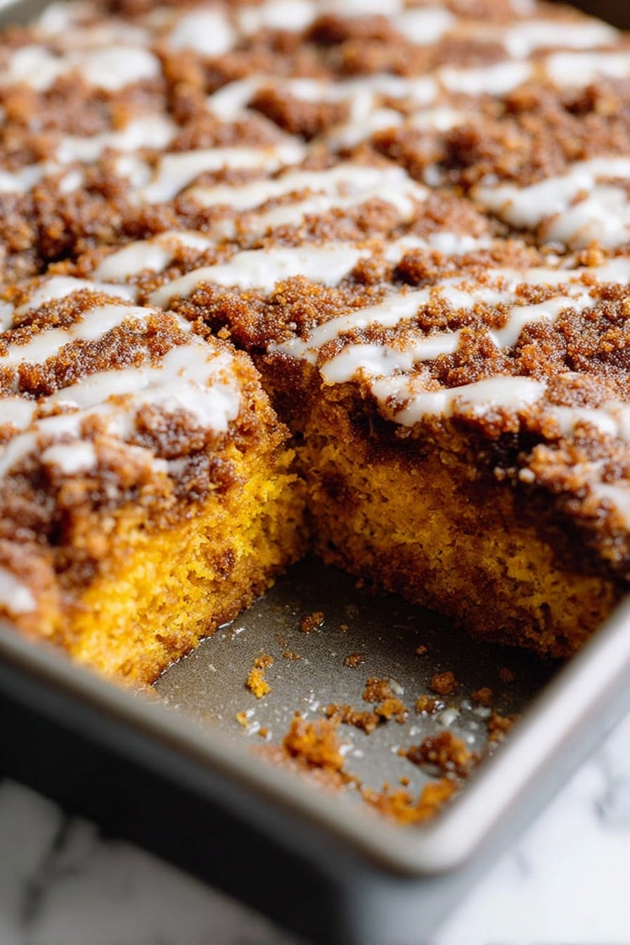 Pumpkin Coffee Cake with Streusel Topping and Optional Glaze, fall coffee cake recipes, pumpkin dessert ideas, cozy pumpkin breakfast, quick pumpkin coffee cake - A close-up view of a rectangular metal baking pan filled with a baked dish divided into nine square pieces. The top layer is a golden brown crust with a rough, crumbly texture and slight darker spots, suggesting a crispy surface. Beneath the crust, there are hints of a soft, orange layer peeking through in a few spots, showing a moist filling. The pan is placed on a wire rack with a dark surface underneath, creating a rustic feel. photo taken with an iphone --ar 2:3 --v 7
