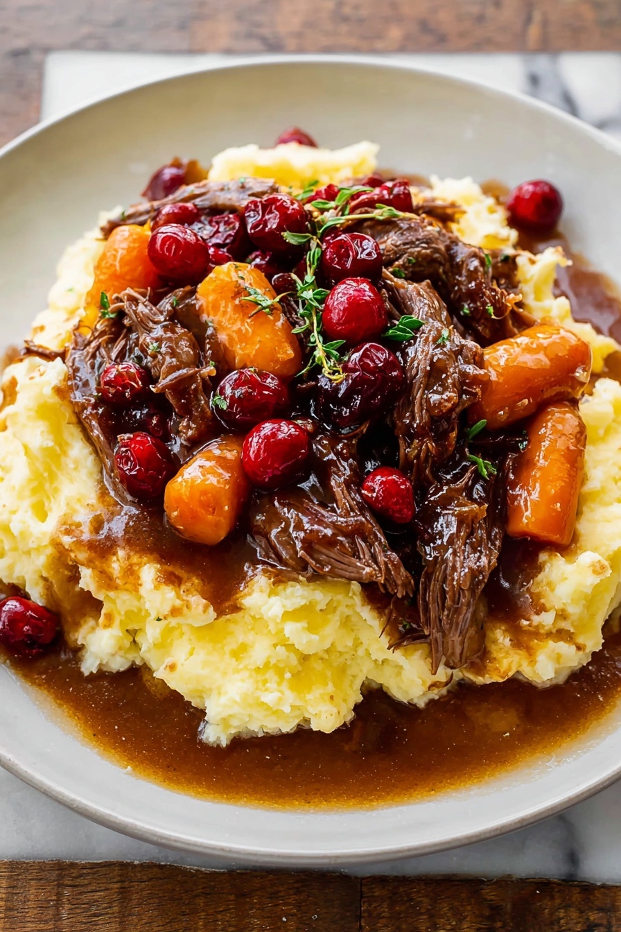 Cranberry Balsamic Roast Beef, Roast Beef with Cranberries and Balsamic, Holiday Roast Beef Recipes, Tender Slow-Cooked Beef with Cranberries, Unique Roast Beef Ideas - A white plate holds a dish with three main layers: the base is a thick, creamy mashed potato layer, pale yellow and textured with soft peaks; on top of that sits a rich brown gravy mixed with tender, shredded dark brown beef pieces; the top layer features bright orange carrot slices and glossy red cranberries scattered throughout, with small green herb sprigs for garnish. The gravy looks shiny and slightly thick, pooling a little on the plate around the mashed potatoes. The whole plate is on a white marbled surface. photo taken with an iphone --ar 2:3 --v 7