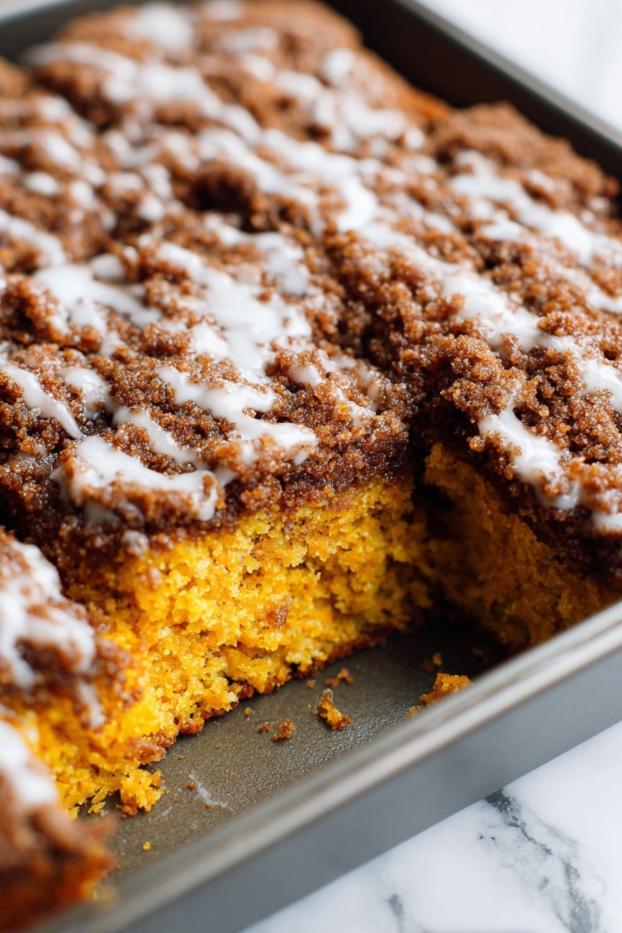 Pumpkin Coffee Cake with Streusel Topping and Optional Glaze, fall coffee cake recipes, pumpkin dessert ideas, cozy pumpkin breakfast, quick pumpkin coffee cake - A close-up view of a square cake in a baking pan, showing one large piece missing from the corner of the cake. The cake has two visible layers: the bottom layer is bright orange with a moist and soft texture, and the top layer is thick with a dark brown crumbly topping mixed with a white glaze lightly drizzled over it. The baking pan is metallic, and the background surface is a white marbled texture. photo taken with an iphone --ar 2:3 --v 7