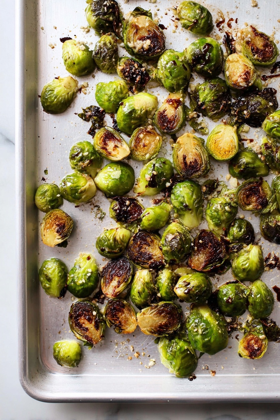 Best Roasted Brussels Sprouts, healthy roasted Brussels sprouts, easy Brussels sprouts recipe, crispy roasted Brussels sprouts, caramelized Brussels sprouts - The image shows a single layer of roasted Brussels sprouts spread out on a white baking sheet. The Brussels sprouts are halved or quartered, with some pieces whole, and they have a mix of bright green and dark brown charred edges. Small bits of garlic and coarse salt are scattered on top, adding texture. There are also spots of dark balsamic glaze drizzled over some of the sprouts. The white baking sheet sits on a white marbled surface, with light reflecting softly on it. photo taken with an iphone --ar 2:3 --v 7