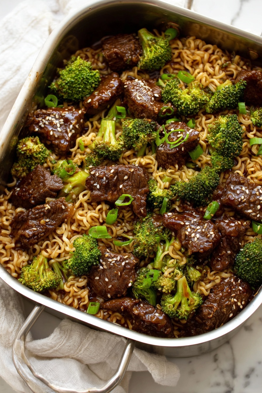 Beef Broccoli Ramen Stir-Fry, quick Asian stir-fry, easy beef ramen dinner, healthy noodle stir-fry, flavorful beef broccoli dish - A metal pan filled with a mixture of three main layers: the first layer is curly light brown noodles that look soft and slippery, the second layer is bright green broccoli florets spread evenly, and the third layer is dark brown pieces of cooked beef scattered throughout. The beef pieces have a shiny glaze on them and some white sesame seeds sprinkled on top. Small pieces of chopped green onion add small bright green spots among the noodles and beef, all resting on a white marbled surface with a white cloth in the background. photo taken with an iphone --ar 2:3 --v 7