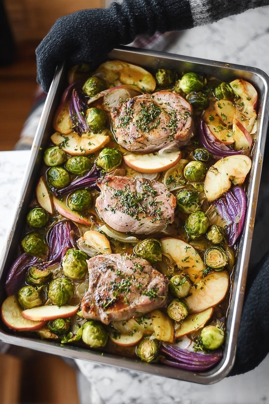 Sheet Pan Pork Chop Supper with Apples, Brussels Sprouts, and Sage, one-pan pork chop dinner, easy sheet pan pork recipes, healthy pork chop meals, flavorful apple and Brussels sprouts dinner - A metal baking tray with four large light pink pork pieces in the center, sprinkled with green herbs, surrounded by bright green halved Brussels sprouts and wedges of purple-red onion and golden brown apple slices, all on a white marbled surface. Steam rises from the tray, held by a woman’s hand wearing a black glove on the left side. The vegetables and pork look roasted with some browned edges. photo taken with an iphone --ar 2:3 --v 7