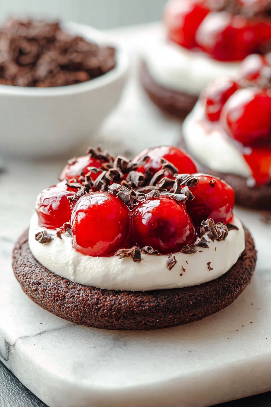 Chocolate Cherry Cheesecake Cookies, chocolate cherry cookie recipe, cheesecake cookies with cherry topping, chocolate cherry dessert cookies, easy chocolate cherry cookies - The image shows a dessert with three layers on a white marbled surface. The bottom layer is a thick, round dark brown chocolate cookie with a coarse texture. The middle layer is a white creamy topping, spread evenly in a smooth circle covering the cookie’s surface. On top, there is a shiny bright red cherry topping that looks wet and glossy, with whole cherries visible. Small dark brown curled chocolate pieces are sprinkled over the cherry topping and creamy layer, adding texture and contrast. In the background, a white bowl filled with more dark brown chocolate curls is blurred, along with a second dessert of the same kind slightly out of focus. photo taken with an iphone --ar 2:3 --v 7