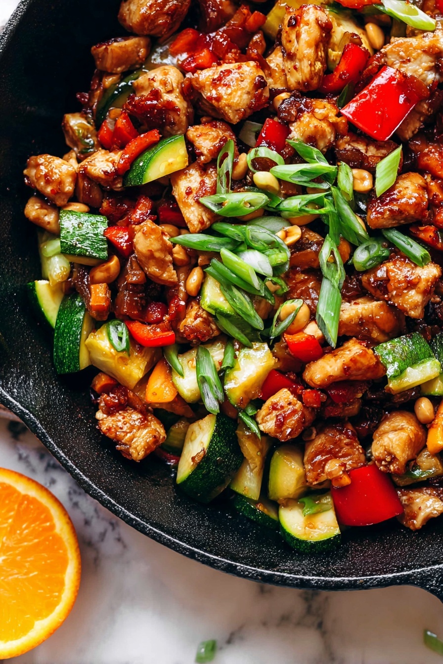 Kung Pao Chicken, Chinese stir-fry, spicy chicken recipe, homemade Chinese chicken, flavorful Asian chicken - The image shows a close-up of a black cast iron pan filled with a colorful stir-fry dish that has three main layers. The first layer has browned chicken cubes with a shiny, caramelized texture scattered throughout the pan. The second layer has chopped vegetables, including bright red bell peppers and chunks of green zucchini with a cooked but firm look. The third layer is made up of small, light brown peanuts and thin slices of green onions sprinkled on top, adding a fresh touch. The pan sits on a white marbled surface, and there is a slice of bright orange on the edge of the pan. The light in the photo makes the food look vibrant and appetizing photo taken with an iphone --ar 2:3 --v 7