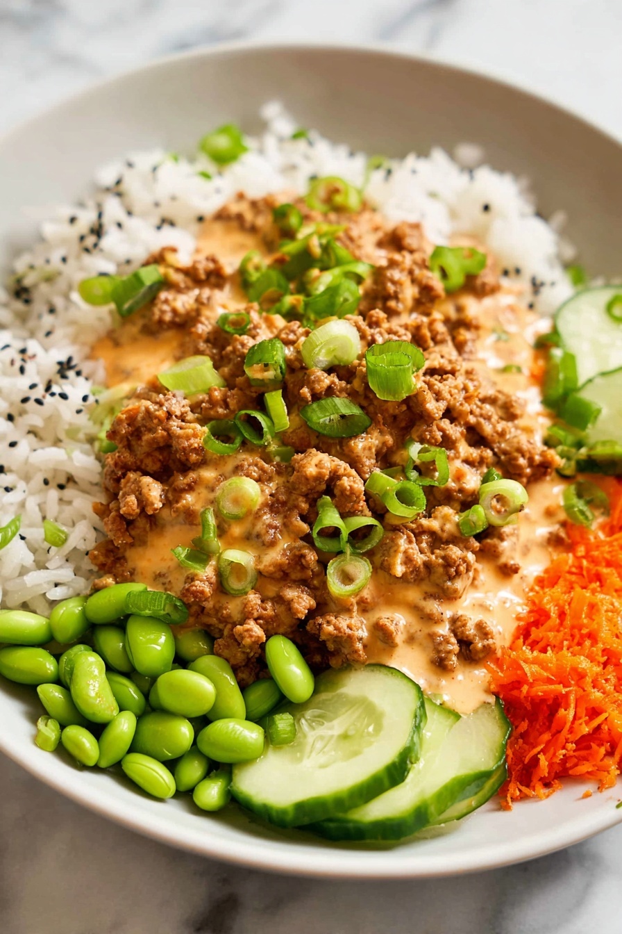 Ground Turkey Rice Bowls with Bang Bang Sauce, quick healthy dinner ideas, easy ground turkey recipes, flavorful rice bowl recipes, spicy bang bang sauce dishes - A white plate holds a colorful, layered meal starting with a base of white rice scattered with small black seeds. On top of the rice, there is a generous layer of brown ground meat covered in a creamy, light orange sauce. Bright green sliced scallions are sprinkled over the meat and sauce. Around the main layers are small piles of bright green edamame, thin slices of cucumber, and grated orange carrots, all sitting on a white marbled surface. Photo taken with an iphone --ar 2:3 --v 7