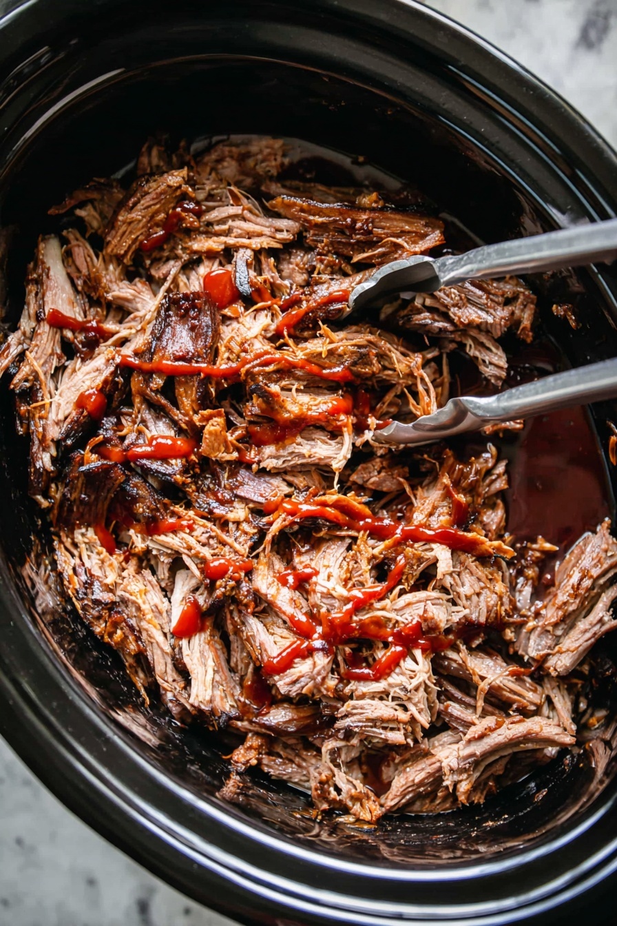 Slow Cooker Pulled Pork, easy pulled pork recipe, tender pork shoulder, smoky pulled pork, homemade pulled pork - A close-up image of shredded cooked meat with dark brown edges and lighter brown inside, placed inside a black slow cooker. The meat is covered with red sauce drizzled unevenly over the top. A silver fork and silver tongs are partially visible inside the slow cooker, placed on the left and right sides of the meat. The slow cooker sits on a white marbled surface. photo taken with an iphone --ar 2:3 --v 7