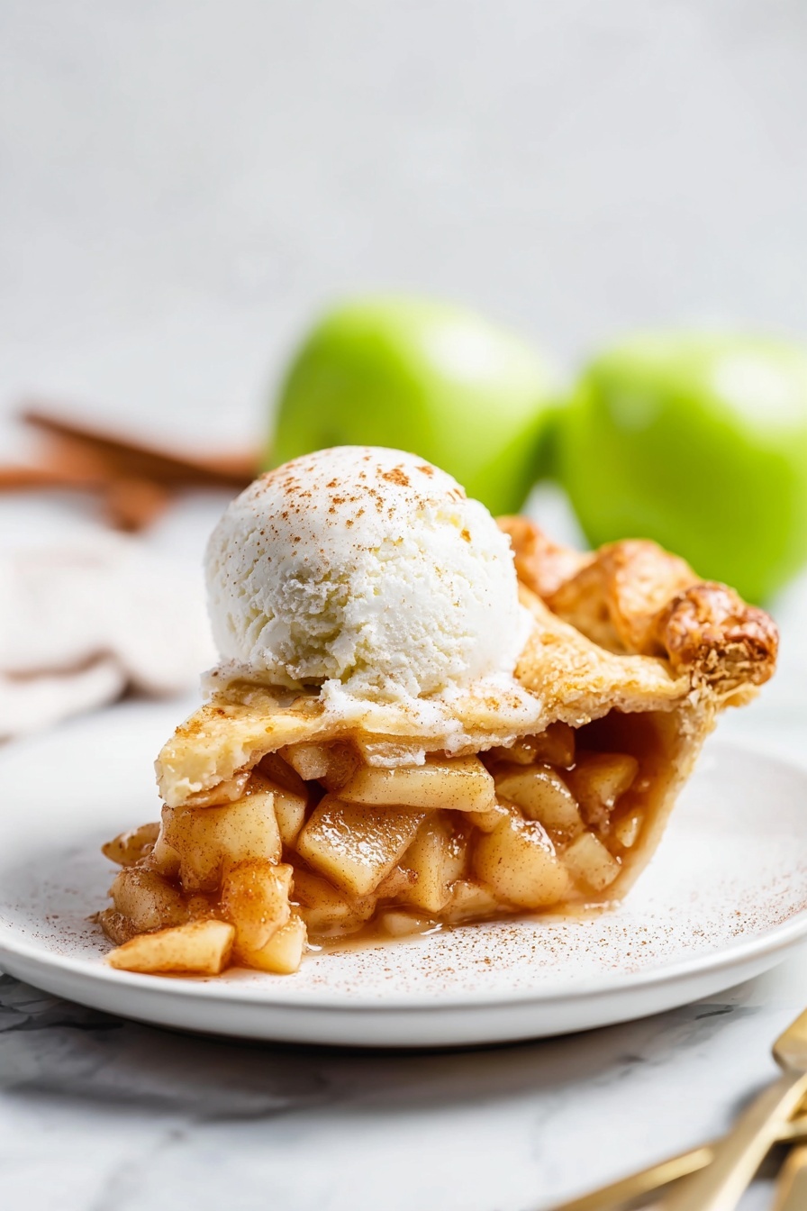 Vegan Pear Pie with Chai Spices, vegan pear pie, chai spiced dessert, dairy-free fruit pie, autumn vegan dessert - A slice of apple pie sits on a white plate, showing three main layers: the bottom crust is golden brown and slightly flaky, the middle layer is filled with soft, cinnamon-spiced apple pieces that look juicy and tender, and the top crust is also golden with a slight sprinkle of sugar. On top of the pie slice is a round scoop of white ice cream with a light dusting of cinnamon. The plate rests on a white marbled surface, and in the background, out of focus, two green apples and a fork and knife are visible. Photo taken with an iphone --ar 2:3 --v 7