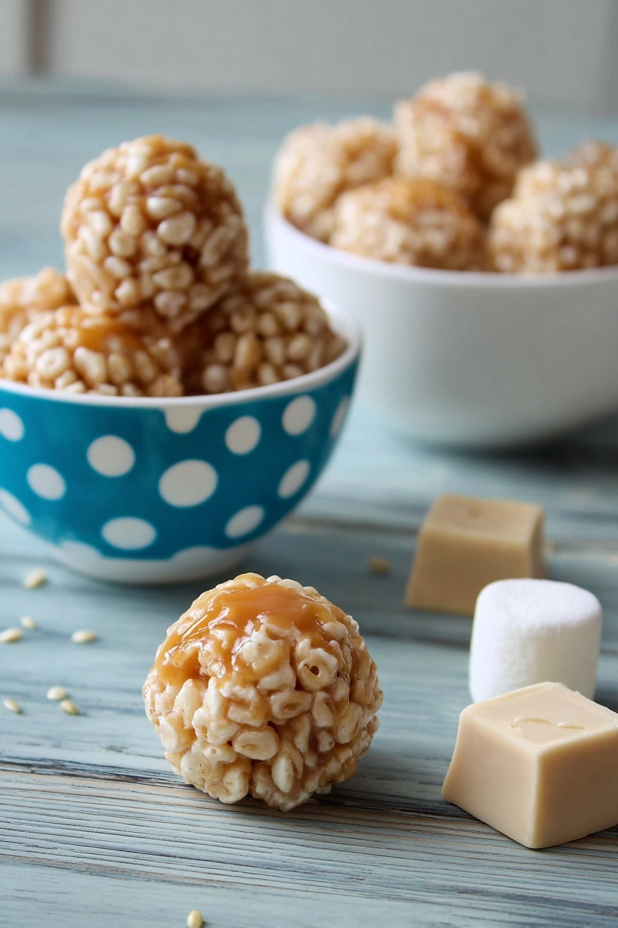 Marshmallow Caramel Rice Krispies Puffs, Rice Krispies treats with caramel and marshmallows, easy caramel marshmallow snack, gourmet Rice Krispies squares, crowd-pleasing holiday treats - The image shows small round treats with a light caramel center covered in a layer of puffed rice. There are three of these treats inside a white bowl with blue and white polka dots on the left side of the image, and a white bowl filled with more treats is in the background on a white marbled surface. Two caramel squares and a large white marshmallow are placed behind one treat in the middle foreground, and a single treat sits on the white marbled surface near the front. The treat's outer puffed rice layer is beige and textured, while the caramel inside is shiny and smooth. photo taken with an iphone --ar 2:3 --v 7