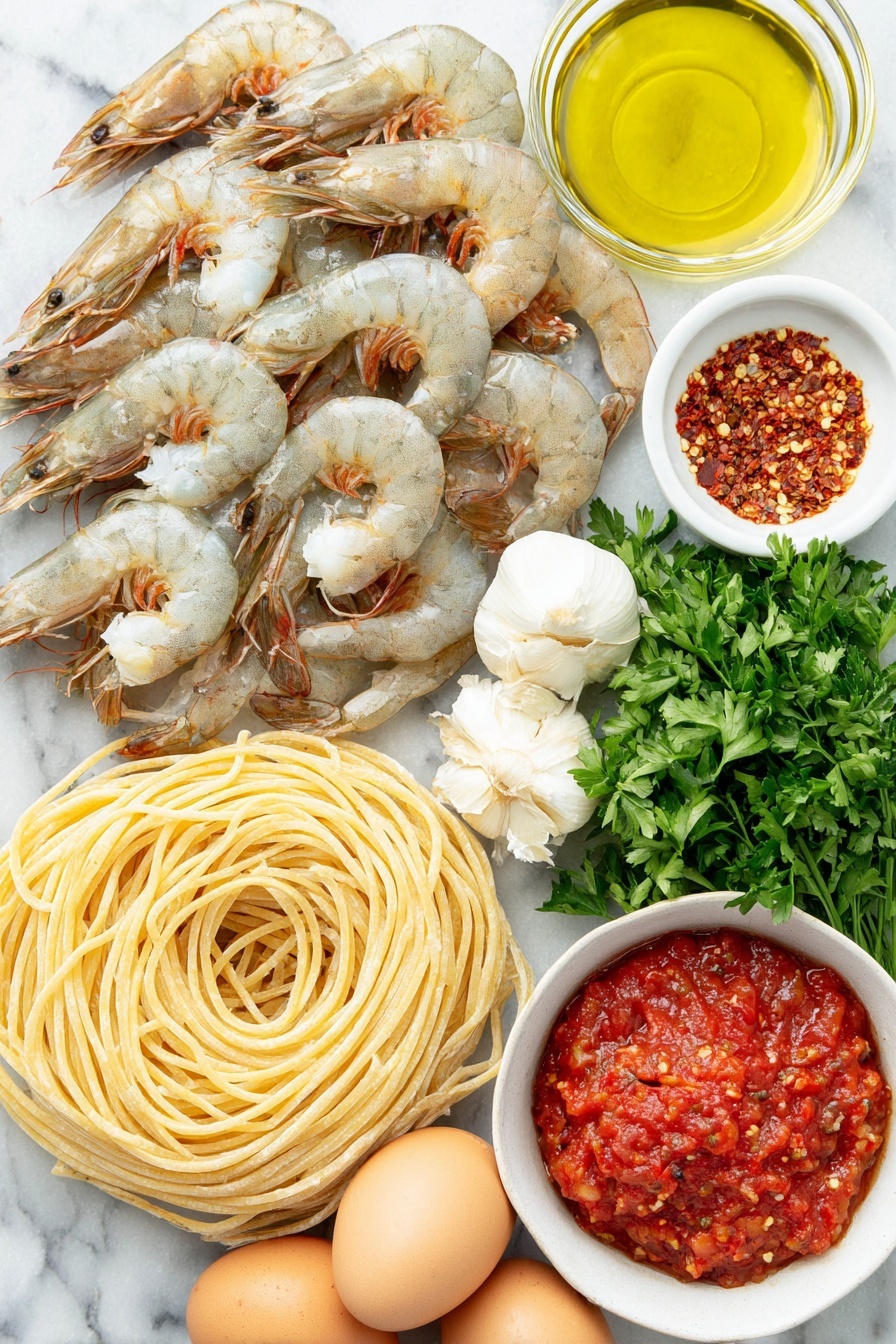 Shrimp Fra Diavolo Pasta, spicy seafood pasta, quick Italian dinner, easy shrimp pasta recipe, flavorful seafood pasta - Flat lay of dry linguine pasta neatly coiled, plump large shrimp with tails on arranged in a gentle curve, a small white bowl filled with shiny olive oil, a small white bowl containing bright red Calabrian chili paste, a cluster of fresh garlic cloves with papery skins intact, a small white bowl of vivid red crushed San Marzano tomatoes, fresh vibrant green parsley sprigs artistically placed, a small white bowl holding mixed red pepper flakes, and three whole uncracked brown eggs arranged symmetrically, all placed on a clean white marble surface, soft natural light, photo taken with an iPhone, professional food photography style, fresh ingredients, white ceramic bowls, no bottles, no duplicates, no utensils, no packaging --ar 2:3 --v 7 --p m7354615311229779997