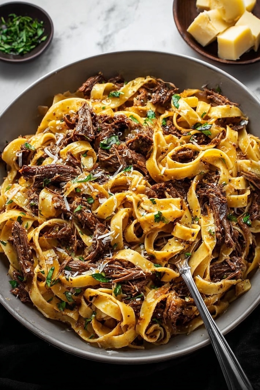 Short Rib Ragu, short rib ragu recipe, hearty beef ragu, slow-cooker ragu, Italian beef stew - A large white bowl filled with a generous serving of tagliatelle pasta mixed with shredded dark brown meat pieces. The pasta is light golden yellow with a slight shine, entwined among the tender meat chunks. Fresh green herb leaves are scattered on top, adding a touch of color and freshness. A small metal fork is placed inside the bowl, partly twirling some pasta and meat. In the background, a small bowl holds chunks of light yellow cheese, and everything is set against a white marbled surface. Photo taken with an iphone --ar 2:3 --v 7