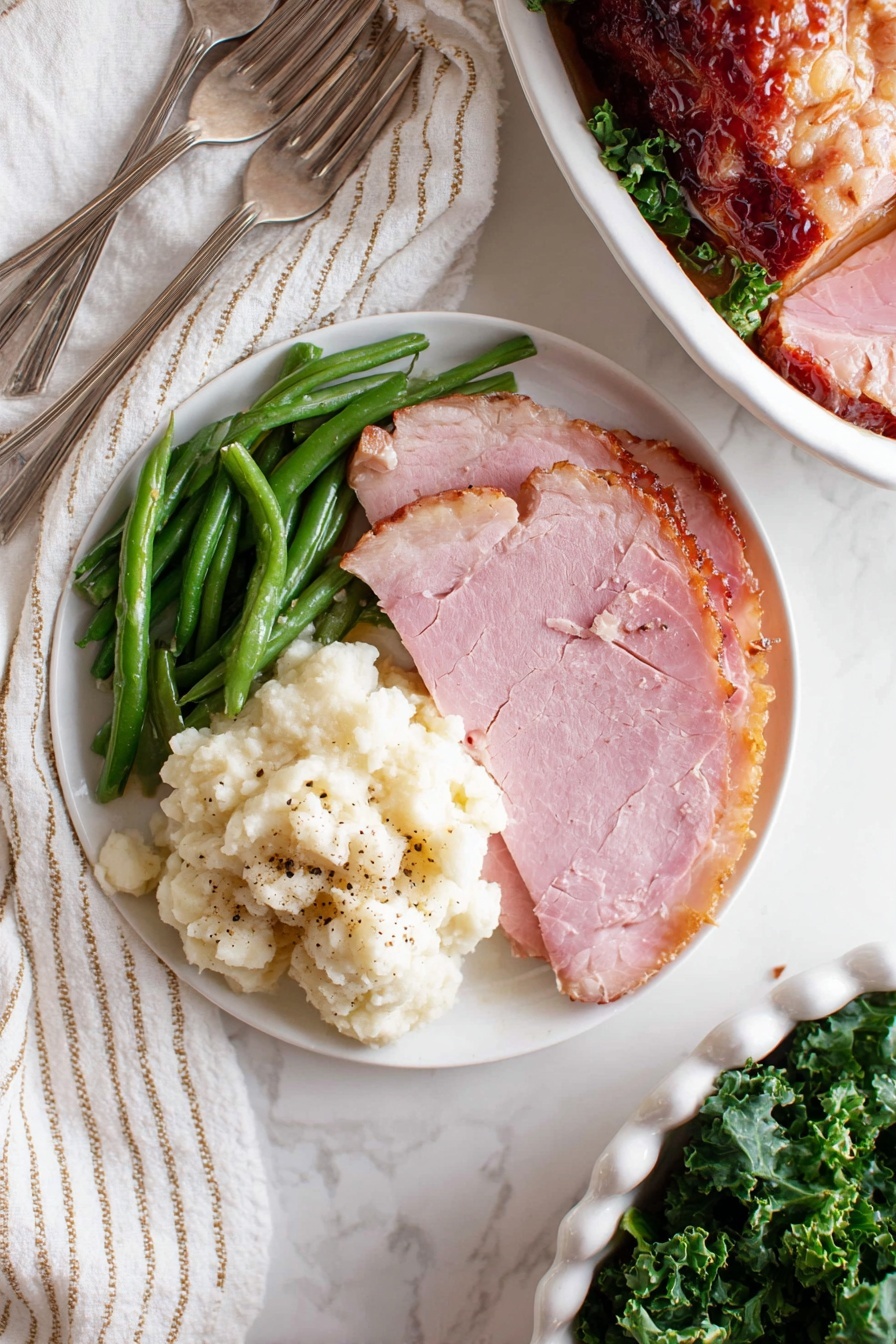 Baked Glazed Ham, glazed ham recipe, holiday ham, easy ham glaze, tender baked ham - A white round plate shows a simple meal with three parts: green beans on the top left, fluffy mashed potatoes with some black pepper on the bottom left, and two thick slices of pink ham on the right, with a light brown edge. The plate sits on a white marbled surface with a white and beige striped cloth on the top left and two silver forks below the plate. On the right top corner, there is a partial view of another white round plate with a slice of ham and green beans. In the bottom right, a white dish filled with sliced glazed ham resting on green leafy kale is partially shown. photo taken with an iphone --ar 2:3 --v 7