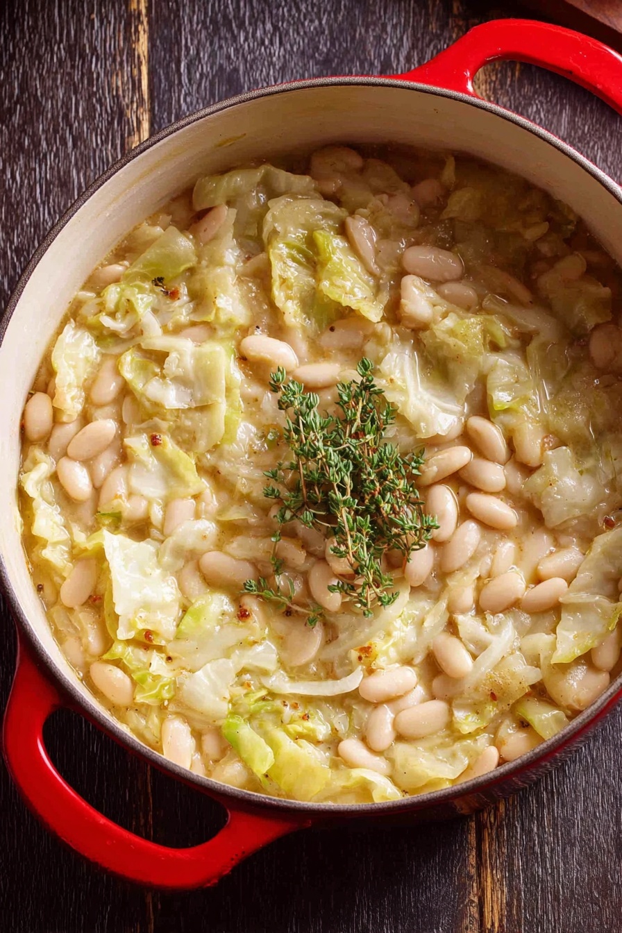 Creamy Butter Beans with Leeks, Creamy Butter Beans with Leeks recipe, easy vegan butter bean dish, hearty leek and bean main, comforting vegetarian meal - A close-up view of a red pot filled with a thick stew made of white beans and chopped light green cabbage in a creamy broth. The stew shows soft textures with some beans floating on top mixed with pieces of cabbage, and it is garnished with a small bunch of fresh green thyme placed in the center. The pot is resting on a dark wooden surface. photo taken with an iphone --ar 2:3 --v 7