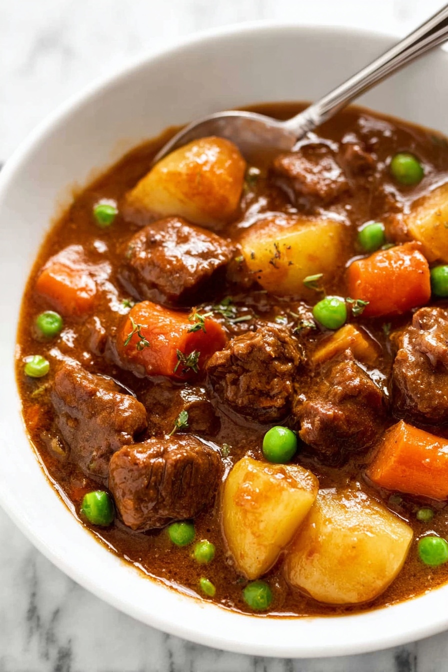 Slow Cooker Beef Stew with Red Wine, Beef Stew with Red Wine, Crockpot Beef Stew, Hearty Beef Stew Recipe, Easy Beef Stew with Wine - A white bowl filled with a stew showing three main layers: soft brown beef chunks covered in a shiny brown sauce, orange carrot pieces, and small green peas scattered around; small quartered light yellow potatoes are submerged in the thick sauce. A silver spoon rests in the bowl, partially visible at the top edge. The background shows a white marbled texture. photo taken with an iphone --ar 2:3 --v 7