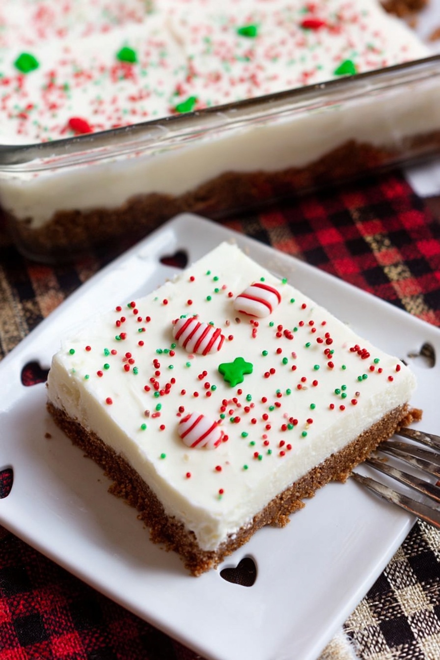 Spiced Gingerbread Cookie Bars, gingerbread bar recipe, holiday cookie bars, soft chewy gingerbread, festive dessert bars - A square dessert bar is shown on a white plate with small heart-shaped cutouts around the edge. The dessert has two clear layers: the bottom layer is a brown, crumbly crust, and the top layer is a thick, smooth, white cream. The white layer is decorated with small round sprinkles in red, green, and white colors, with a pair of white candy pieces with red and green stripes placed near the center. The dessert and plate sit on a wooden surface with a red, black, and beige checkered cloth nearby. Part of a glass baking dish filled with the same dessert and a smiling ceramic cup are visible in the background. A woman's hand holds a fork resting on the plate. photo taken with an iphone --ar 2:3 --v 7