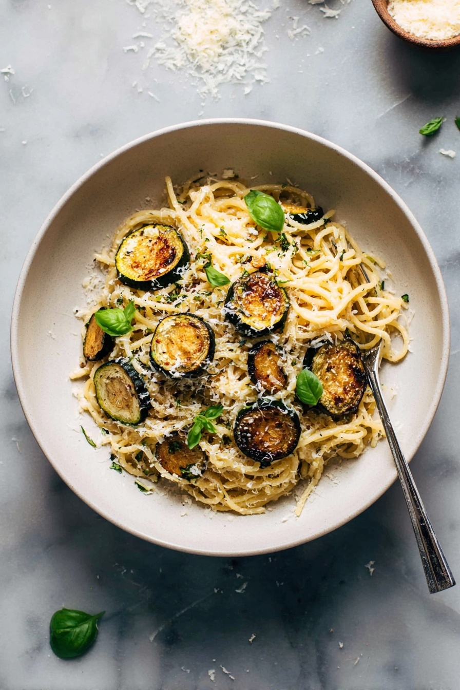 Spaghetti with Crispy Zucchini and Parmesan, zucchini pasta with parmesan, crispy zucchini spaghetti, easy zucchini pasta recipe, flavorful zucchini pasta dish - A white bowl filled with a mound of spaghetti pasta at the center, topped with several golden-brown, round slices of roasted zucchini scattered on and around the noodles. Small bright green basil leaves are placed over the pasta, adding a fresh touch. The spaghetti is sprinkled with finely grated white cheese, giving a light dusting over the top. A silver fork rests on the right side inside the bowl. The bowl is set on a white marbled surface with some scattered grated cheese and a few basil leaves nearby. Photo taken with an iphone --ar 2:3 --v 7