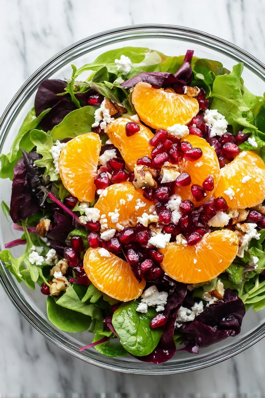 Winter Salad with Citrus and Pomegranate, citrus winter salad, pomegranate salad recipe, healthy winter salad, easy citrus salad - A large clear glass bowl filled with a fresh salad containing several layers: at the bottom, a mix of green leafy spinach and lettuce with dark purple leaves, topped with bright orange mandarin slices scattered evenly. On top of this are small red pomegranate seeds sprinkled throughout, along with crumbled white cheese and small brown nut pieces. The colors are vivid and fresh, and the textures range from soft leaves to juicy fruit and crunchy nuts, all sitting on a white marbled surface. Photo taken with an iphone --ar 2:3 --v 7
