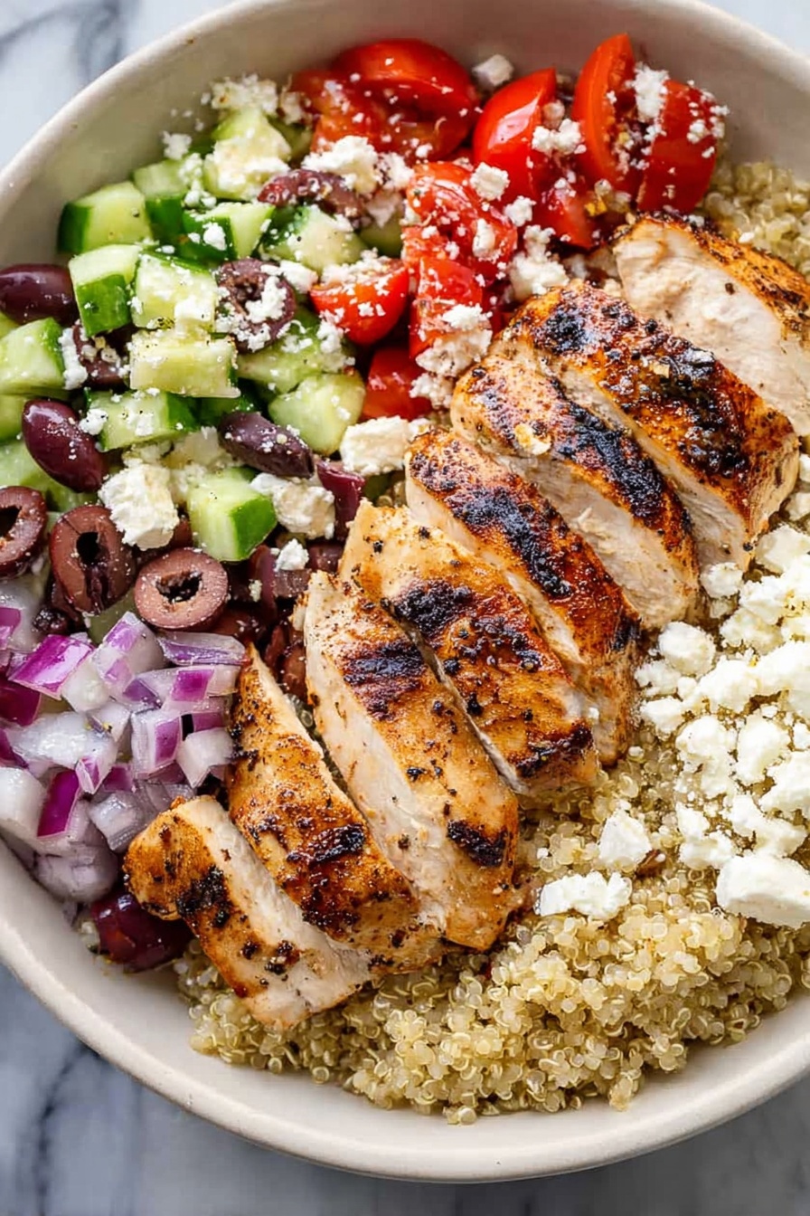 Greek Chicken Quinoa Bowls, Greek Chicken Bowls, Healthy Quinoa Bowls, Mediterranean Chicken Recipe, Fresh Chicken Quinoa Dinner - A white bowl holds a colorful layered dish on a white marbled surface. The bottom layer is light beige quinoa. On top of this, sliced grilled chicken with visible char marks sits to one side. To the right of the chicken is a mix of chopped red tomatoes and small pieces of red onion. Below the tomato mix is chopped green cucumber with some purple olives scattered throughout. White crumbled cheese is sprinkled over the top of the tomatoes, cucumbers, and olives. The colors contrast well, showing fresh and healthy ingredients. Photo taken with an iphone --ar 2:3 --v 7