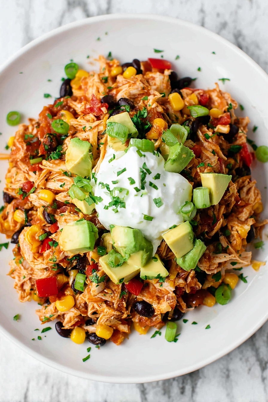 Easy Chicken Burrito Casserole, chicken burrito casserole, stovetop chicken casserole, easy dinner ideas, weeknight casserole recipes - A white plate holds a colorful mixture of shredded chicken mixed with black beans, bright yellow corn, and small red pepper pieces, all evenly mixed together. On top are scattered chunks of green avocado and sliced green onions, adding fresh color. In the middle of the pile, there is a dollop of white sour cream. Some small green herb bits are sprinkled over the dish and around the plate edge. The plate sits on a white marbled surface. photo taken with an iphone --ar 2:3 --v 7