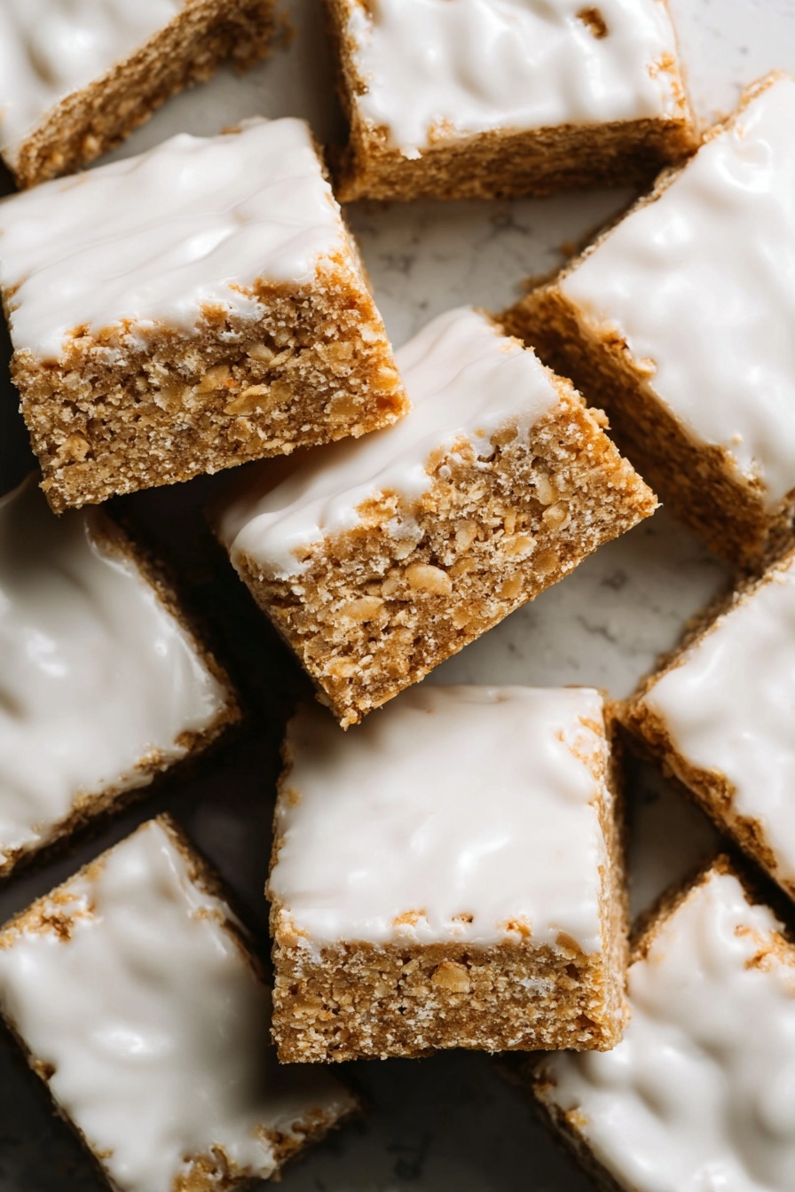 Iced Oatmeal Cookie Bars, oatmeal cookie bars, cinnamon dessert bars, vanilla glazed cookie bars, no-bake oat bars - The image shows many square bars stacked closely together, each bar having two visible layers. The bottom layer is a light brown, crumbly, and textured base that looks like a oat or cookie mixture. The top layer is a shiny white icing that spreads unevenly across the surface, with some areas thicker and others showing the brown base underneath. The bars look soft but firm, with rough edges and a slightly grainy texture. The whole setup is on a white marbled surface. photo taken with an iphone --ar 2:3 --v 7